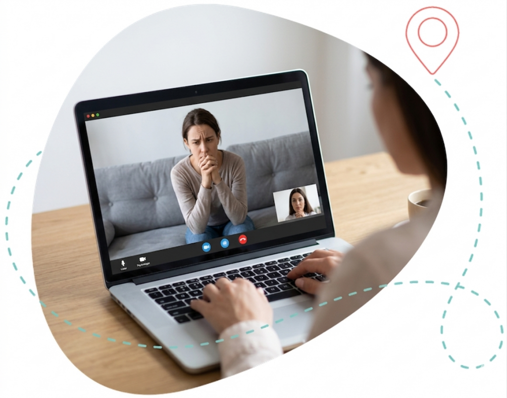 imagen en forma amorfa con línea punteada azul y pin rojo. En su interior, una sesión de psicología online: un portátil sobre una mesa muestra a una persona preocupada en videollamada mientras una psicóloga la escucha.